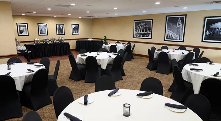 Fully catered private dining area. Room is filled with black chairs and white tablecloths.