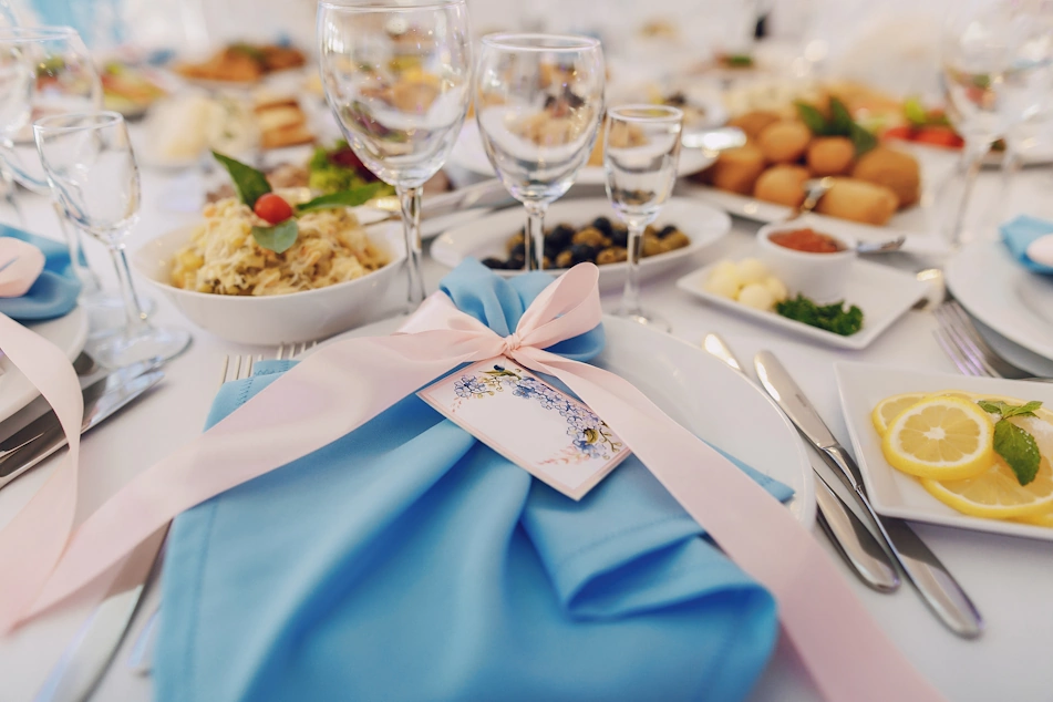 A table with catering meals behind and lovely blue and pink table decoration for a gender reveal party